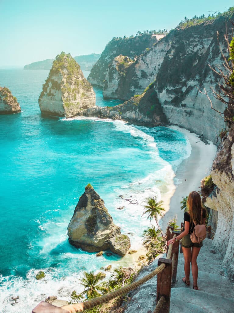 A travel girl with backpack in shorts on the ocean, cliffs and t
